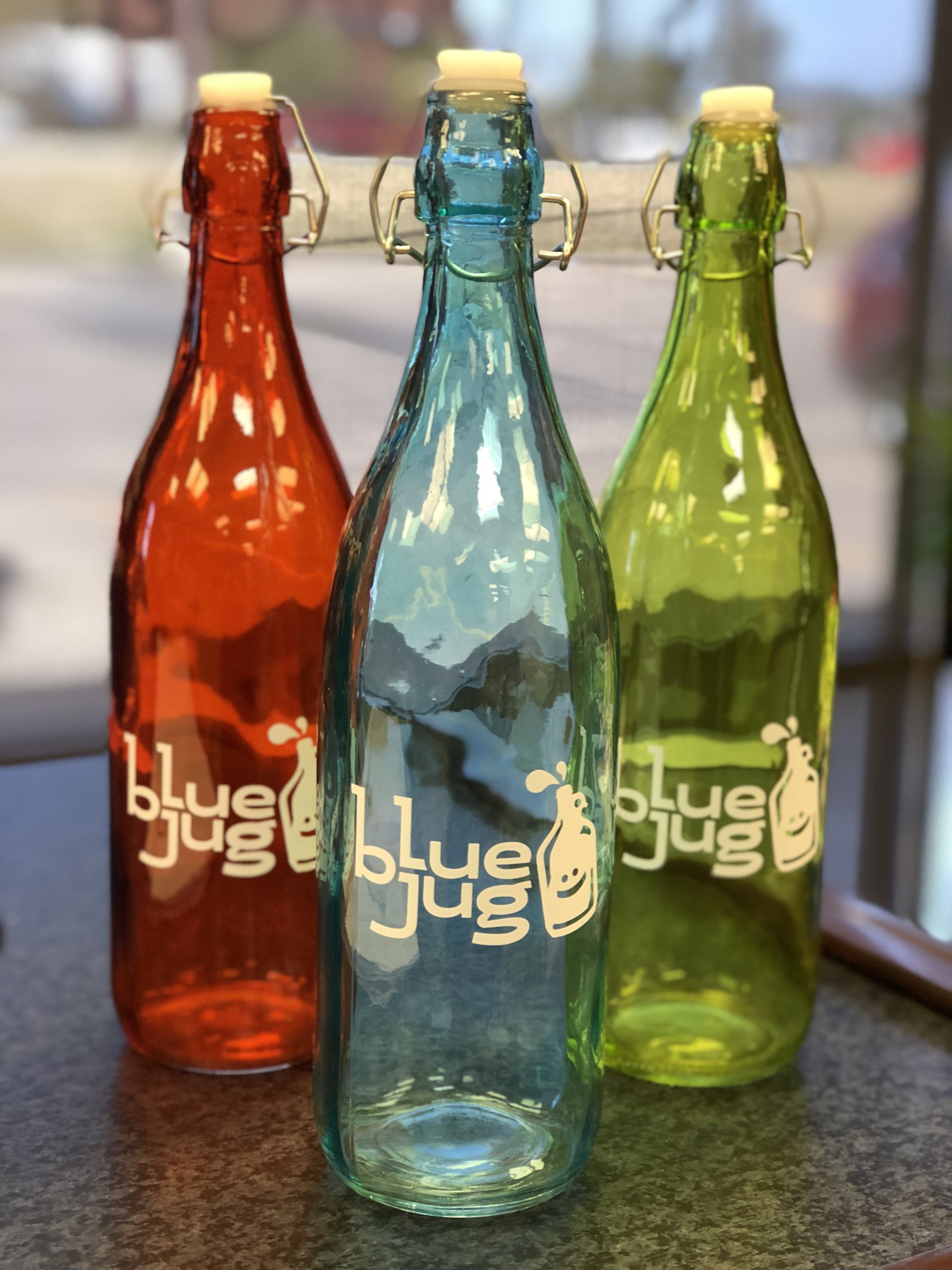 Three vibrant ‘blueJug’ bottles in red, blue, and green